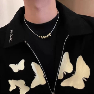 Close-up of silver chain necklace with gold twist knot pendant on a black jacket