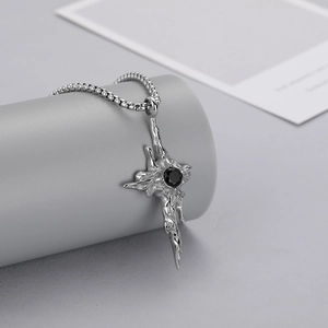 Detail view of a gothic liquid metal cross pendant necklace with a black round stone