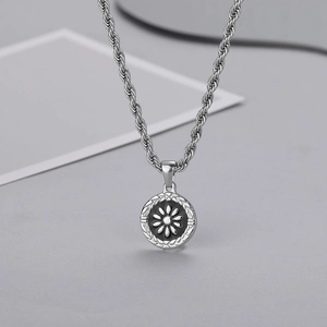 Macro shot of silver daisy coin pendant with twisted rope chain and textured border