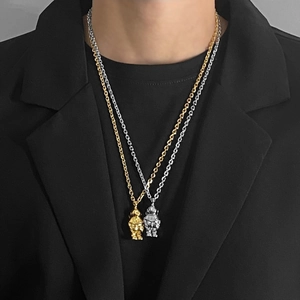 Detailed close-up of astronaut pendant necklaces in gold and silver on a black suit