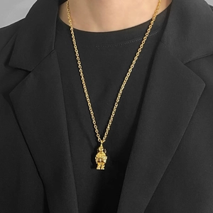 Detail view of a gold astronaut pendant necklace worn over a black blazer for high contrast