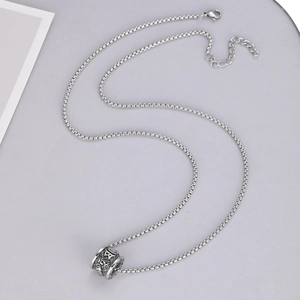 Close-up of a silver stainless steel box chain necklace with an engraved cylinder pendant