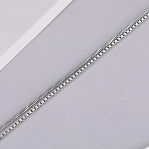 Detail of silver snake bone and box chain necklaces showing polished stainless steel texture