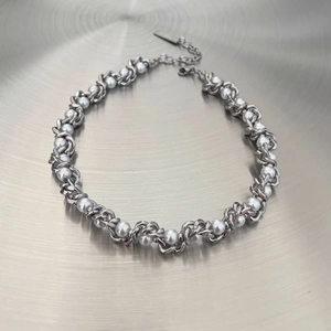 Gros plan d'un collier de perles à maille cubaine avec chaîne argentée et fermoir mousqueton