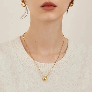 Gros plan d'un collier avec pendentif cœur 3D doré et double chaîne sur un mannequin