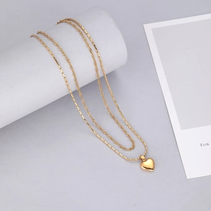 Détail d'un collier double épaisseur en acier titane doré avec pendentif cœur et chaîne