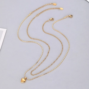 Détail du collier double rang doré avec pendentif cœur 3D et fermoir mousqueton