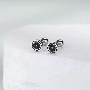 Detail of vintage rudder stud earring with sun pattern on textured white stone