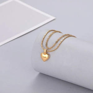 Détail d'un collier double épaisseur cœur doré avec finition miroir sur support