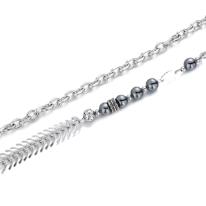 Détail d'un collier en acier avec perles métalliques sombres et pendentif arête
