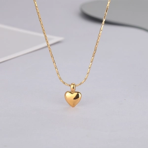 Détail d'un pendentif cœur 3D poli sur une chaîne double couche dorée élégante