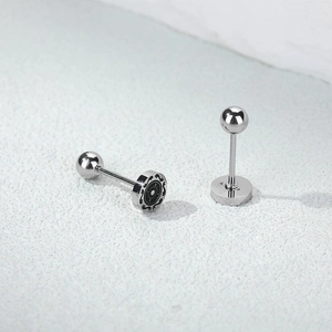 Macro shot of vintage titanium steel barbell earrings with sunburst engraved disc