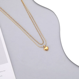 Vue macro détaillée d'un collier double couche doré avec pendentif cœur sur socle gris