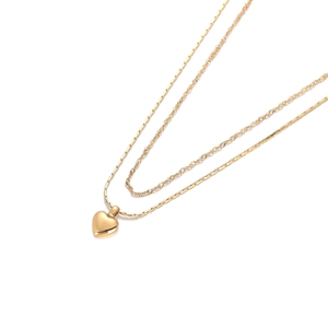 Détail d'un collier doré double épaisseur avec pendentif cœur et chaînes superposées