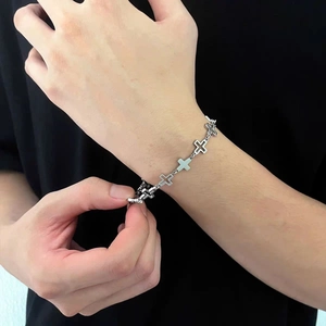 Macro view of polished silver stainless steel hollow cross bracelet worn on male wrist