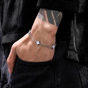 Detail of silver steel cross bracelet with white enamel inlay on black denim