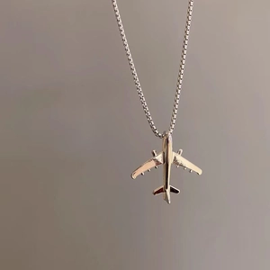 Detailansicht eines silbernen Flugzeuganhängers an einer stilvollen Box-Halskette