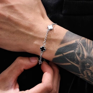 Detailed shot of black and white cross charm on titanium steel chain on male wrist