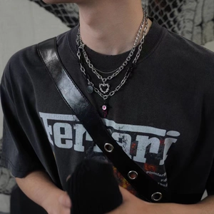 Détail de colliers Y2K superposés avec pendentifs cœur épineux et œil rose