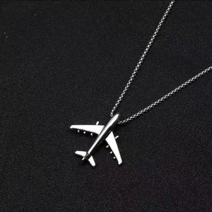 Makroaufnahme eines silbernen Flugzeuganhängers mit realistischen Flügeln an einer Kette