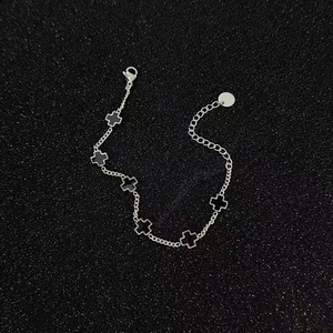 Macro shot of silver titanium steel bracelet with black cross pendants and lobster clasp
