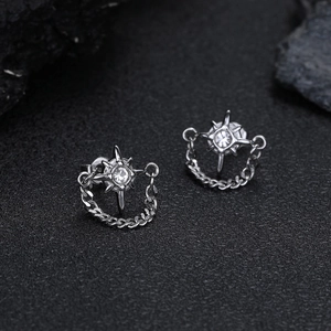 Dettaglio macro di orecchini a stella in argento con zircone e catena stile cubano