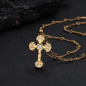 Collier avec pendentif croix baroque dorée et zircons sur fond texturé noir