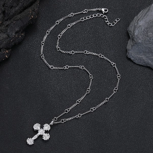 Vue détaillée du pendentif croix en argent avec relief baroque sur fond de pierre noire