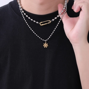 Détail du collier double rang à perles argentées avec pendentif fleur dorée et trombone