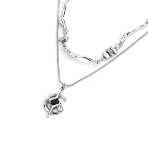 Vue macro du collier double rang avec pendentif étoile, pierre noire et détails de lune argentée