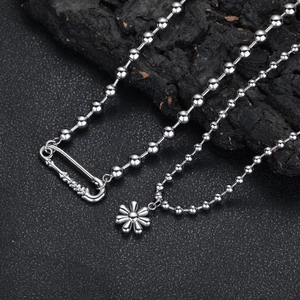Détail macro du collier à billes argenté avec pendentif marguerite et fermoir épingle
