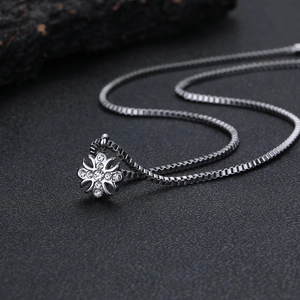 Dettaglio del ciondolo a croce hiphop con cristalli e catena box color argento