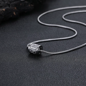 Gros plan du pendentif cylindre rétro avec gravure de mantra sur chaîne serpent