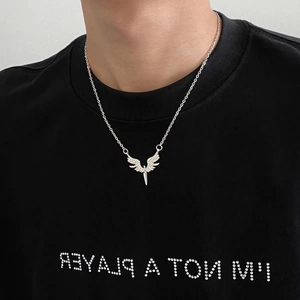 Détail macro du collier pendentif ailes d'ange étincelant porté sur un haut noir