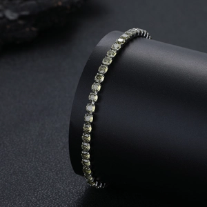 Dettaglio del bracciale tennis con zirconi verdi incastonati su supporto nero lucido
