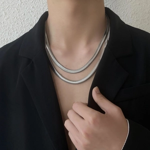 Detail einer zweilagigen silbernen Schlangenkette auf einem schwarzen Sakko getragen