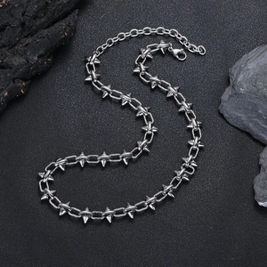 Détail d'un collier punk argenté avec des pointes sur fond de roche texturée