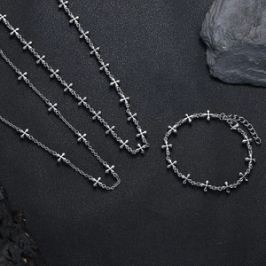 Set collana a croce multistrato e bracciale a catena in argento su sfondo nero opaco