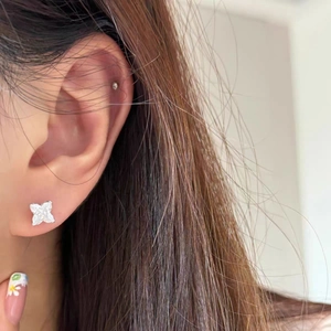 Gros plan de boucles d'oreilles trèfle à quatre feuilles en acier argenté et zircon
