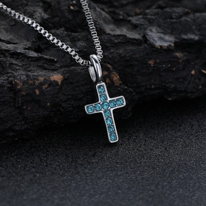 Dettaglio macro della collana a croce in acciaio al titanio con pietre di zircone blu
