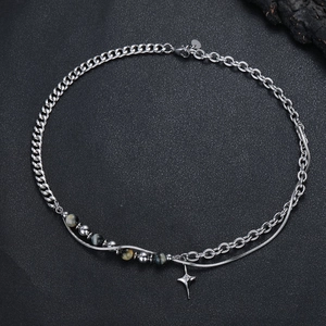 Dettaglio macro del ciondolo a stella e perle occhio di tigre su bracciale in acciaio