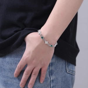 Dettaglio del bracciale a quadrifoglio con pietre verdi indossato su polso modella