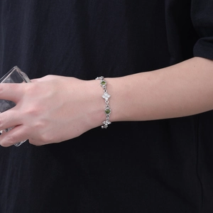 Dettaglio bracciale quadrifoglio in argento con pietre verde oliva e zircone sul polso