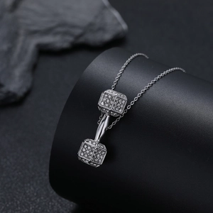 Vue macro du collier avec pendentif haltère argenté serti de pierres en zircon brillant