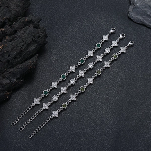 Dettaglio macro di tre braccialetti a quadrifoglio con zirconi verdi e bianchi