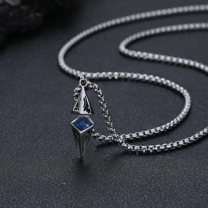 Macro detail of geometric pendant with blue zircon on black textured background