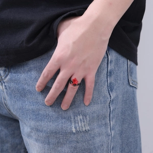 Detailed view of dark gothic red flower ring with black band worn on a finger