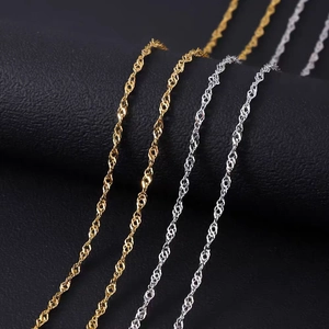 Polished silver and gold water wave link chains displayed on a black leather stand