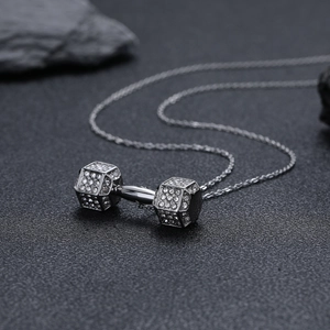 Détail macro du pendentif haltère en argent avec cristaux sur fond texturé sombre