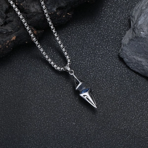Detailed macro of geometric silver pendant with blue zircon on a textured stone
